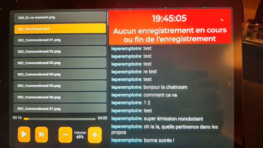 Une tablette avec une page HTML en local

A gauche de l'écran, une playlist VLC avec des boutons de play/pause et de volume, a droite : l'heure, et le chatroom et un code couleur rouge (pour signifier que le festival est en pause)