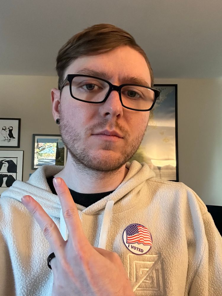 A picture of me in a white Zed hoodie with a sticker that says “I voted”.