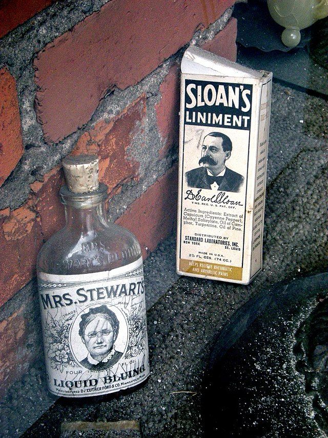 Image of old-timey liniment bottles sitting in front of a brick wall.