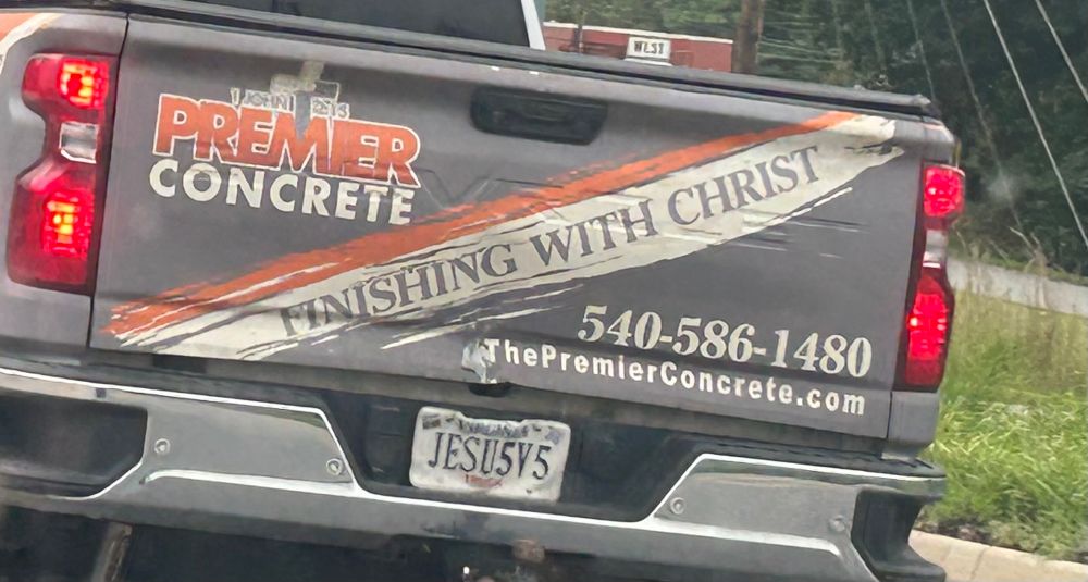 Tailgate of a concrete company pickup truck. The motto “Finishing with Christ” is written diagonally across it.
