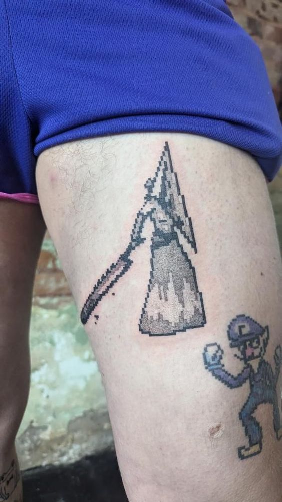 A pixel art tattoo rendition of Pyramid Head, with read around because it's fresh. On the bottom right, we can see a pixelated tattoo of Waluigi.