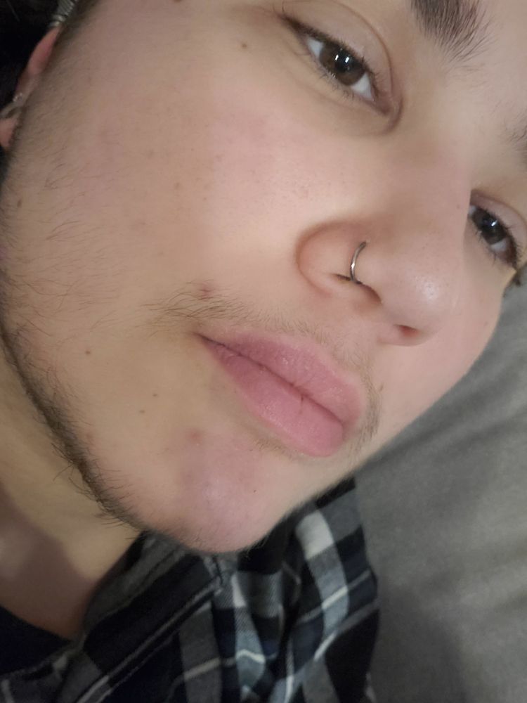 Close-up on a cute androgynous trans person with a small but noticeable mustache.