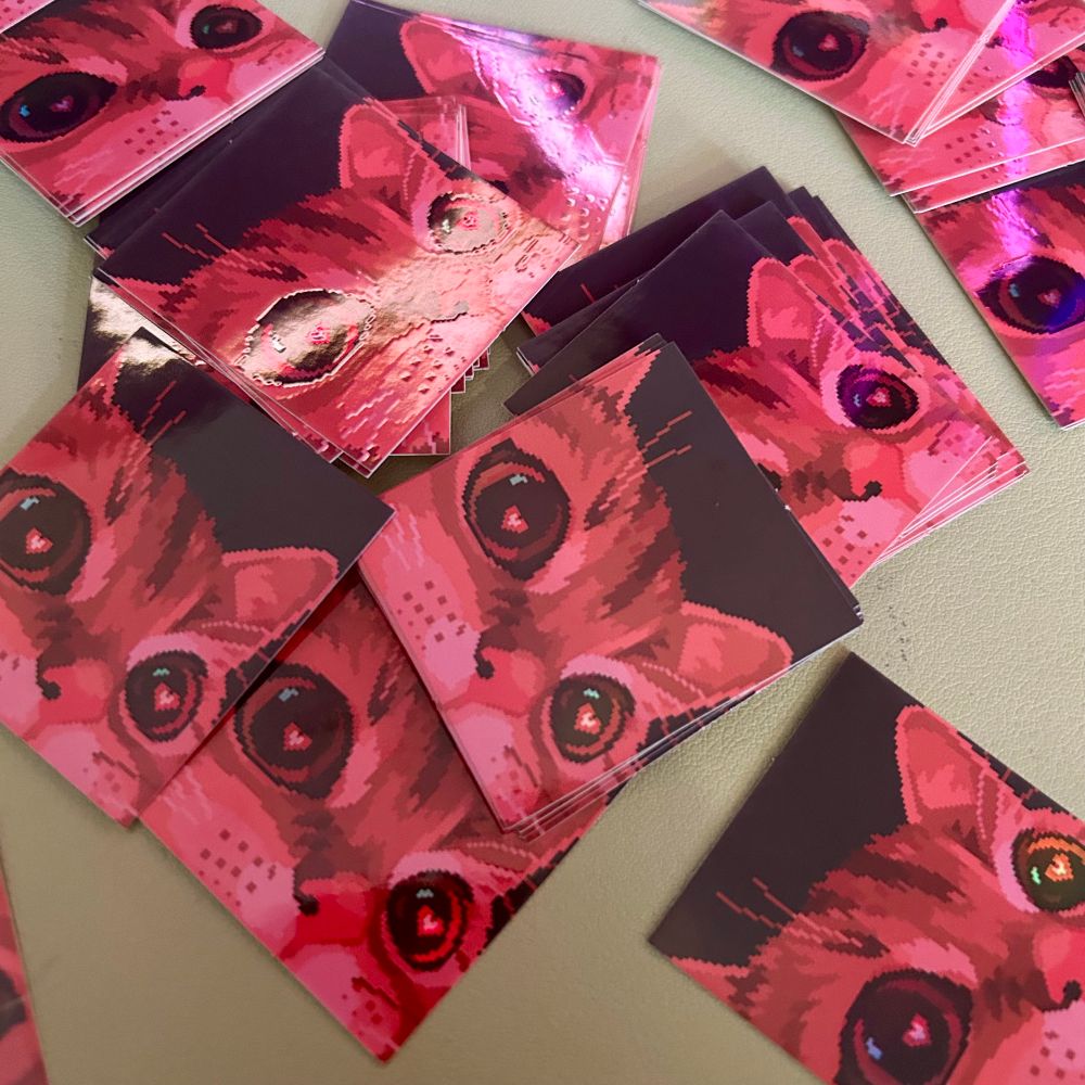 a photograph of some stickers featuring a pixel art cat with hearts in its eyes