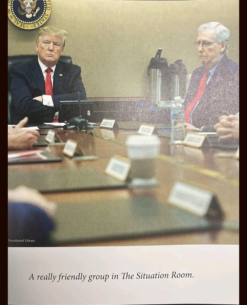 Image from Trump's newest photo book. Image shows Mitch McConnell and Trump at a desk with the text "A really friendly group in the Situation room" underneath 