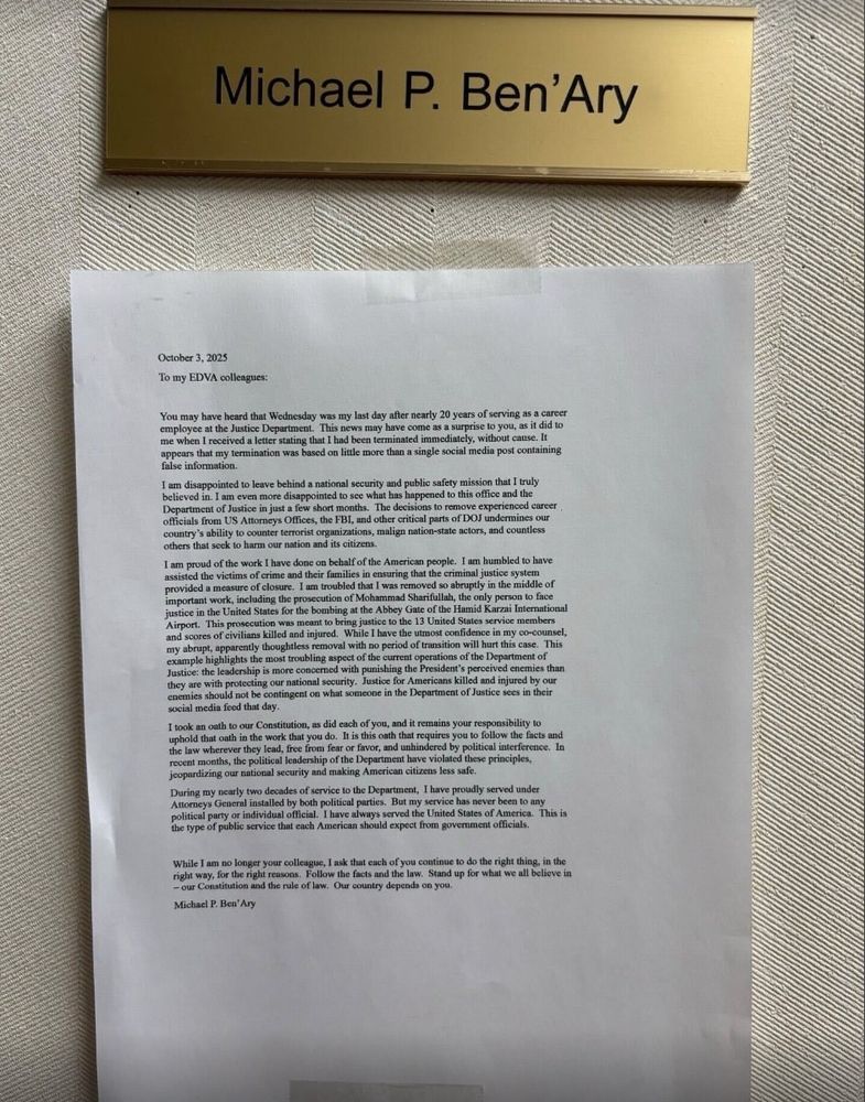 Photo showing a gold nameplate reading "Michael P. Ben'Ary" mounted on a textured beige wall, above a printed letter on white paper. The letter is dated October 3, 2025, and reads:

"To my EDVA colleagues:

You may have heard that Wednesday was my last day after nearly 20 years of serving as a career employee at the Justice Department. This news may have come as a surprise to you, as it did to me when I received a letter stating that I had been terminated immediately, without cause. It appears that my termination was based on little more than a single social media post containing false information.

I am disappointed to leave behind a national security and public safety mission that I truly believed in. I am even more disappointed to see what has happened to this office and the Department of Justice in just a few short months. The decisions to remove experienced career officials from US Attorneys Offices, the FBI, and other critical parts of DOJ undermines our country's ability to counter terrorist organizations, malign nation-state actors, and countless others that seek to harm our nation and its citizens.

I am proud of the work I have done on behalf of the American people. I am humbled to have assisted the victims of crime and their families in ensuring that the criminal justice system provided closure. I am troubled that I was removed so abruptly in the middle of important work, including the prosecution of Mohammad Sharifullah, the only person to face justice in the United States for the bombing at the Abbey Gate of the Hamid Karzai International Airport. This prosecution was meant to bring justice to the 13 United States service members and scores of civilians killed and injured. 
[...]