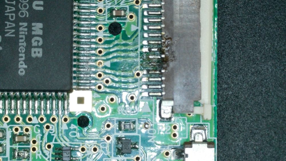 The display ribbon cable connector on a Game Boy Pocket circuit board, with two pins damaged because some idiot has been in here before. (There’s a non-zero chance that idiot was me.)