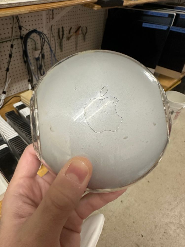 A translucent grey round plastic device with an Apple logo in the center