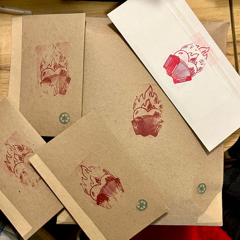 A bunch of packages ready to mail, all with red flamingo accordions stamped in them. 