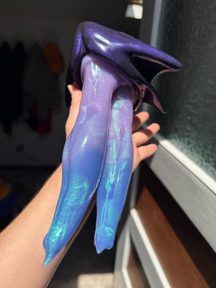 a dildo with a deep purple base, and twin shafts fading from lavender to blue. its in my hand with the tips facing to the bottom left