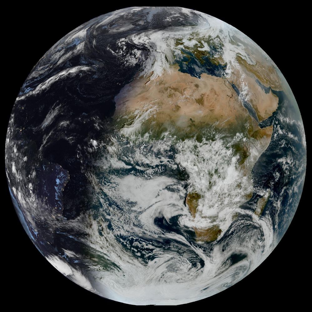 Full disk satellite view of Earth centered on Africa and Europe, with partial views of South America and the Middle East. The satellite image showing Earth from geostationary orbit, captured by EUMETSAT's Meteosat Third Generation (MTG) satellite using the GeoColor RGB composite technique. The image displays both day and night views of Earth, with the daytime portion showing true color representation of land and clouds, while the nighttime portion appears darker with visible city lights. White cloud formations are scattered across the image, particularly along the intertropical convergence zone. The image provides a full disk view of Earth, showing the planet's curvature against a black background.