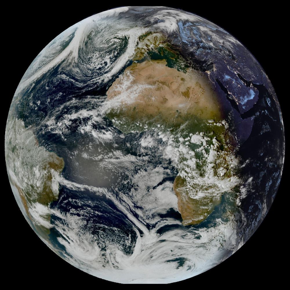 Full disk satellite view of Earth centered on Africa and Europe, with partial views of South America and the Middle East. The satellite image showing Earth from geostationary orbit, captured by EUMETSAT's Meteosat Third Generation (MTG) satellite using the GeoColor RGB composite technique. The image displays both day and night views of Earth, with the daytime portion showing true color representation of land and clouds, while the nighttime portion appears darker with visible city lights. White cloud formations are scattered across the image, particularly along the intertropical convergence zone. The image provides a full disk view of Earth, showing the planet's curvature against a black background.