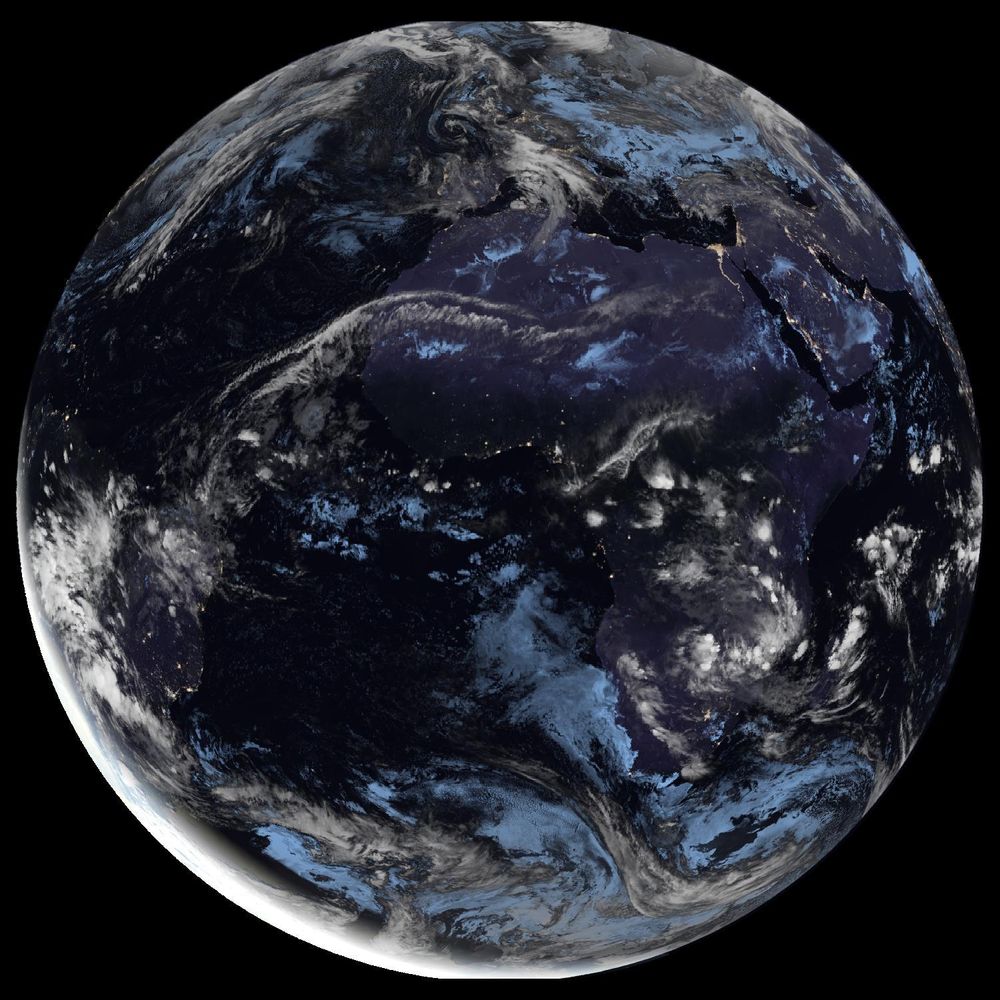 Full disk satellite view of Earth centered on Africa and Europe, with partial views of South America and the Middle East. The satellite image showing Earth from geostationary orbit, captured by EUMETSAT's Meteosat Third Generation (MTG) satellite using the GeoColor RGB composite technique. The image displays both day and night views of Earth, with the daytime portion showing true color representation of land and clouds, while the nighttime portion appears darker with visible city lights. White cloud formations are scattered across the image, particularly along the intertropical convergence zone. The image provides a full disk view of Earth, showing the planet's curvature against a black background.