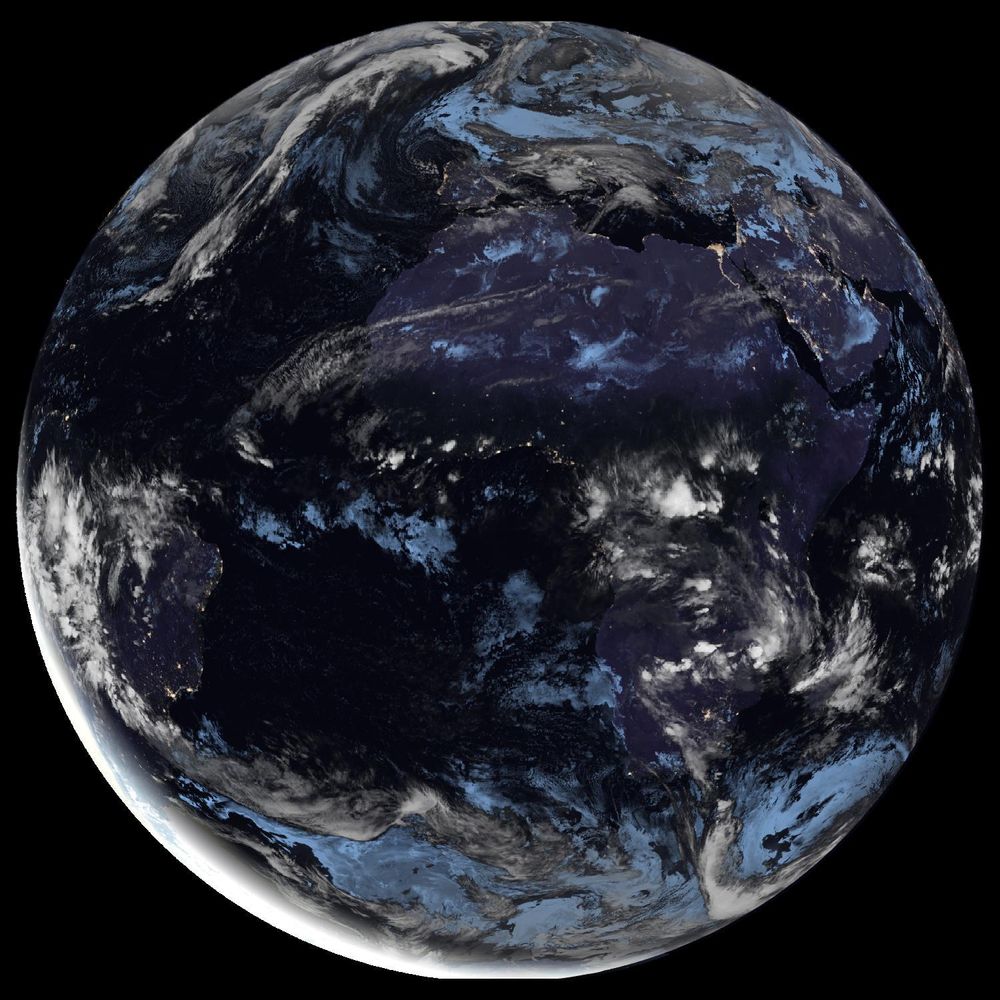 Full disk satellite view of Earth centered on Africa and Europe, with partial views of South America and the Middle East. The satellite image showing Earth from geostationary orbit, captured by EUMETSAT's Meteosat Third Generation (MTG) satellite using the GeoColor RGB composite technique. The image displays both day and night views of Earth, with the daytime portion showing true color representation of land and clouds, while the nighttime portion appears darker with visible city lights. White cloud formations are scattered across the image, particularly along the intertropical convergence zone. The image provides a full disk view of Earth, showing the planet's curvature against a black background.