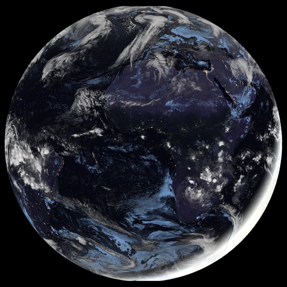 Full disk satellite view of Earth centered on Africa and Europe, with partial views of South America and the Middle East. The satellite image showing Earth from geostationary orbit, captured by EUMETSAT's Meteosat Third Generation (MTG) satellite using the GeoColor RGB composite technique. The image displays both day and night views of Earth, with the daytime portion showing true color representation of land and clouds, while the nighttime portion appears darker with visible city lights. White cloud formations are scattered across the image, particularly along the intertropical convergence zone. The image provides a full disk view of Earth, showing the planet's curvature against a black background.