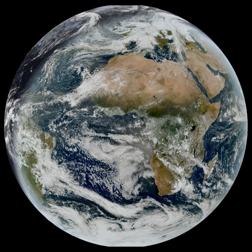 Full disk satellite view of Earth centered on Africa and Europe, with partial views of South America and the Middle East. The satellite image showing Earth from geostationary orbit, captured by EUMETSAT's Meteosat Third Generation (MTG) satellite using the GeoColor RGB composite technique. The image displays both day and night views of Earth, with the daytime portion showing true color representation of land and clouds, while the nighttime portion appears darker with visible city lights. White cloud formations are scattered across the image, particularly along the intertropical convergence zone. The image provides a full disk view of Earth, showing the planet's curvature against a black background.