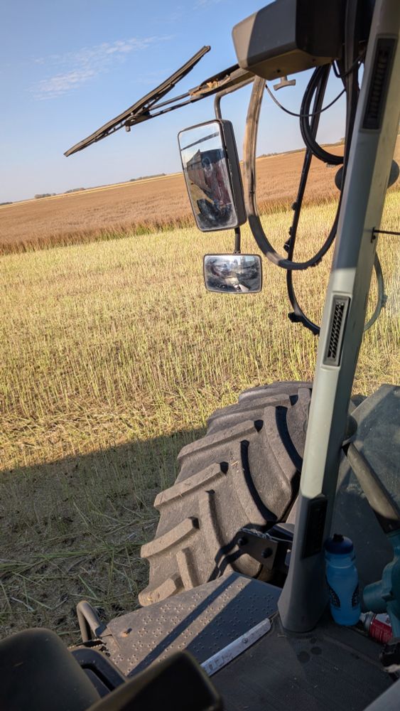 View out the place where a glass door used to be. I'm parked in a canola field on a clear blue windy day. 