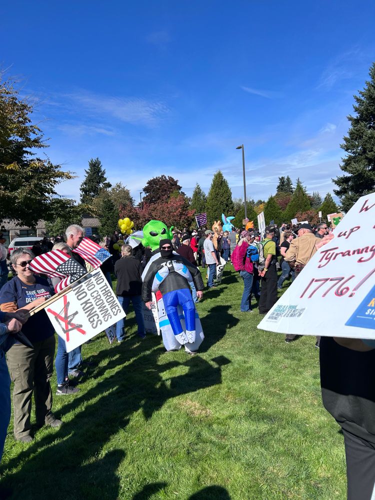 Picture of a man wearing a costume of an alien holding a man wearing an ICE shirt. 