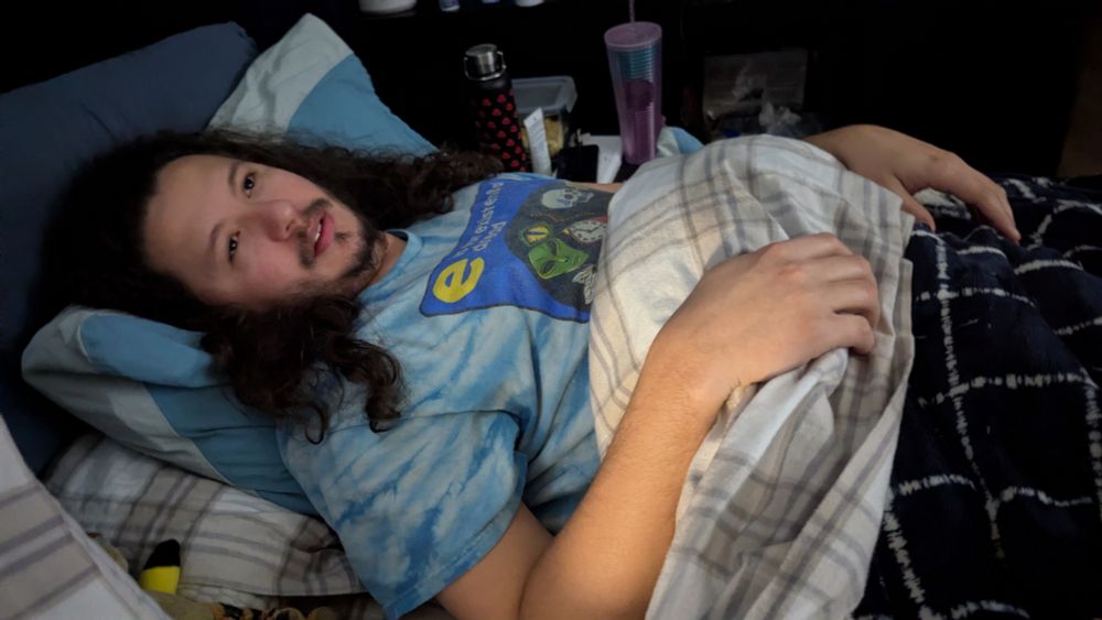 Gustavo homem branco deitado numa cama imitando uma pintura de uma mulher morrendo 