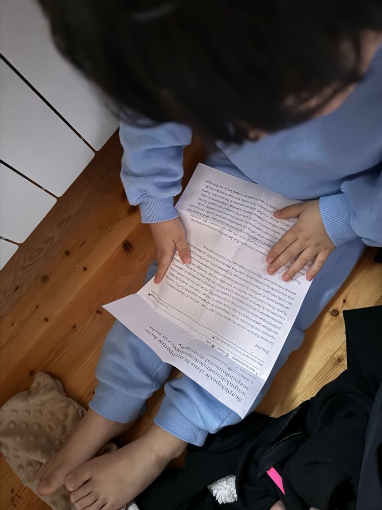 On voit une feuille posée sur des jambes de petit garçon. La feuille est un article scientifique dont le titre est « Scapulopexie dans les myopathies fascié scapulo-humérales » 