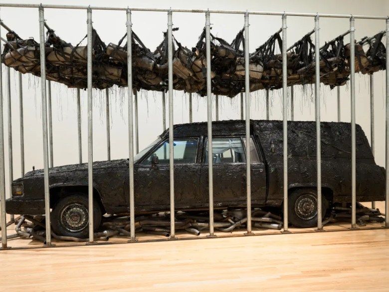 installation image of a parked car that has been covered in black material and installed in a musuem