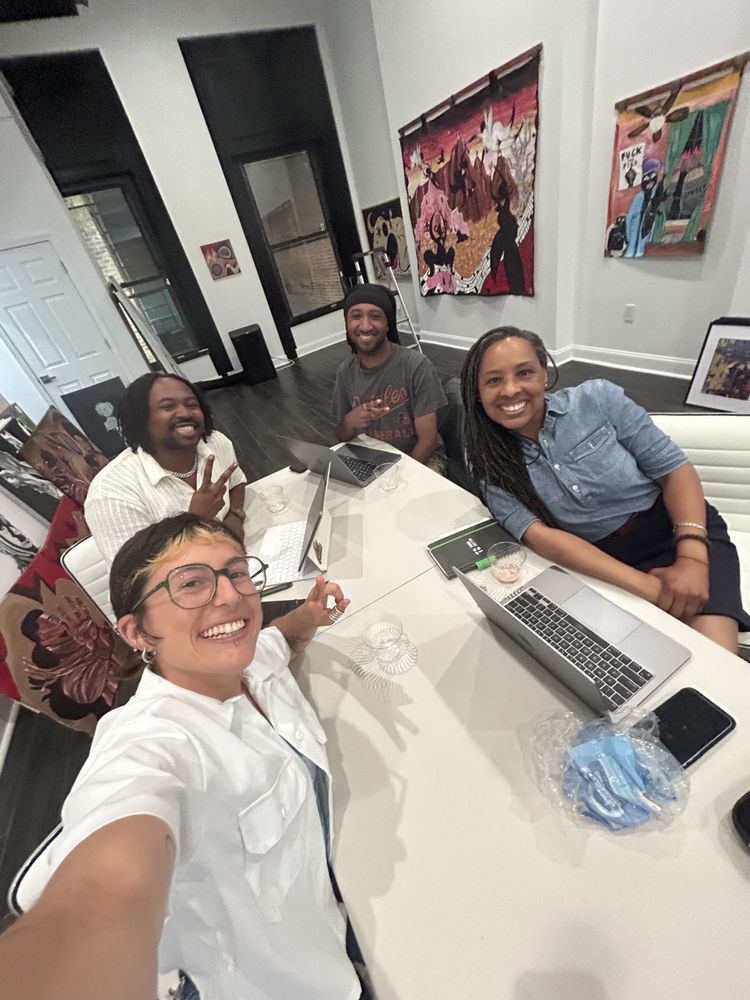 A group of people sitting a conference table smile at the camera.