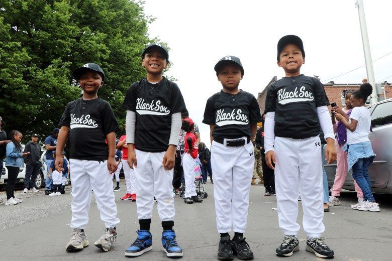 Four young baseball players pose in black and white Black Sox uniforms.