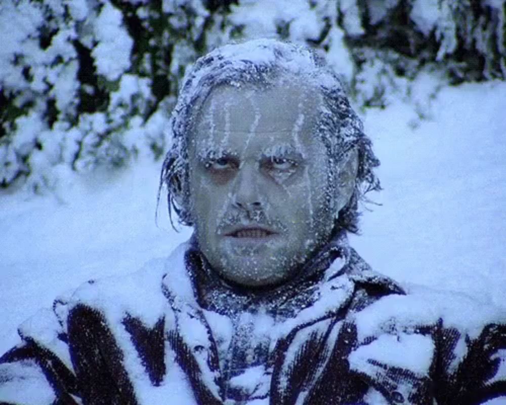 a man with ice on his face is standing in a snowy field