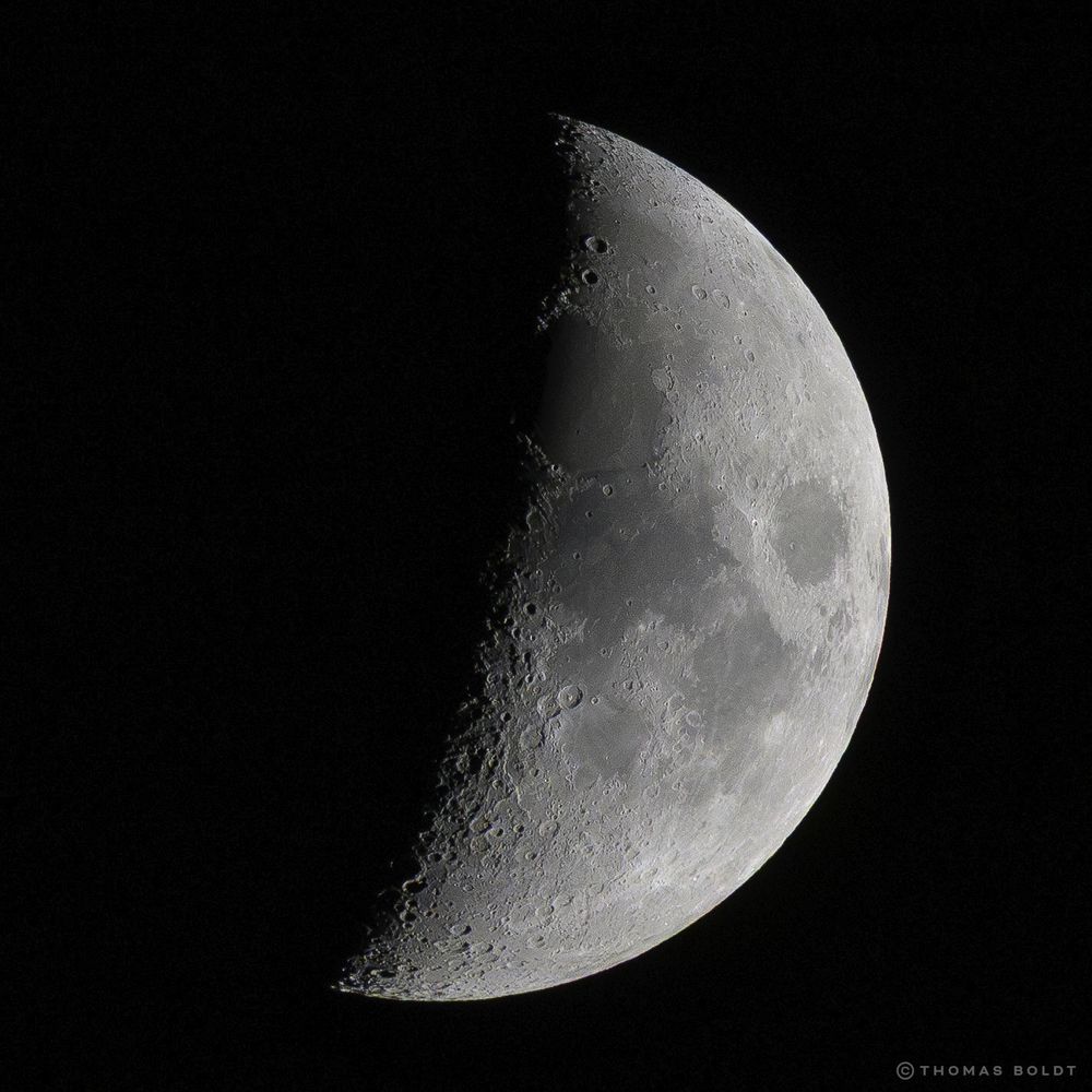 a photograph of the moon, around half full, taken through a 600mm telephoto lens on july 1, 2025
