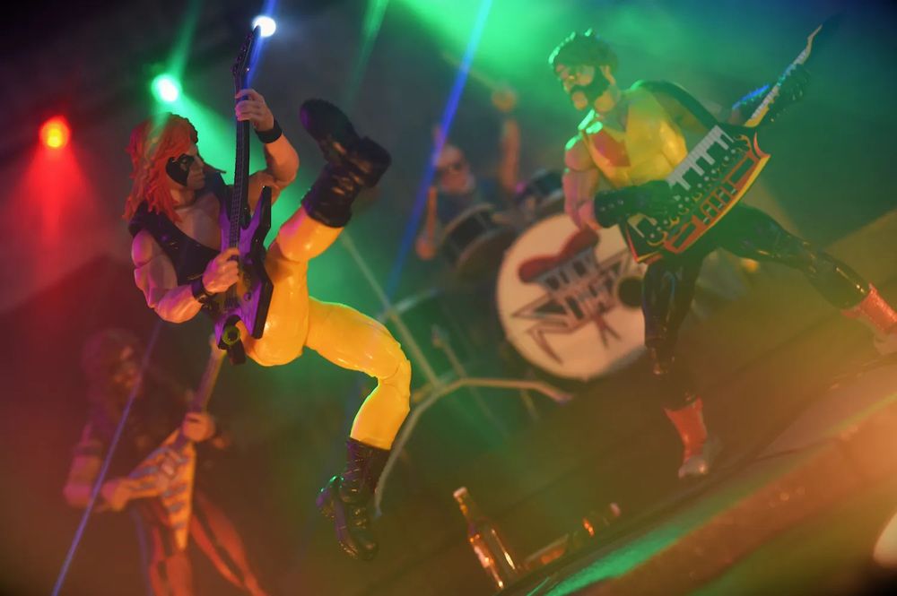 Dreadnok Zartan in cold Slither glam rock disguise jumping through the air playing guitar.