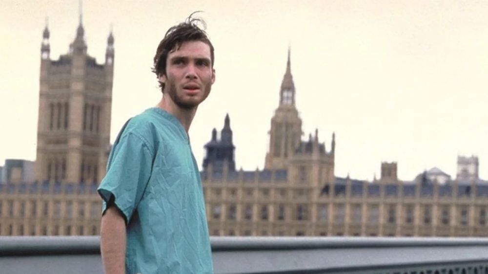A man in a hospital gown stands amid the backdrop of an empty post-apocalyptic London.