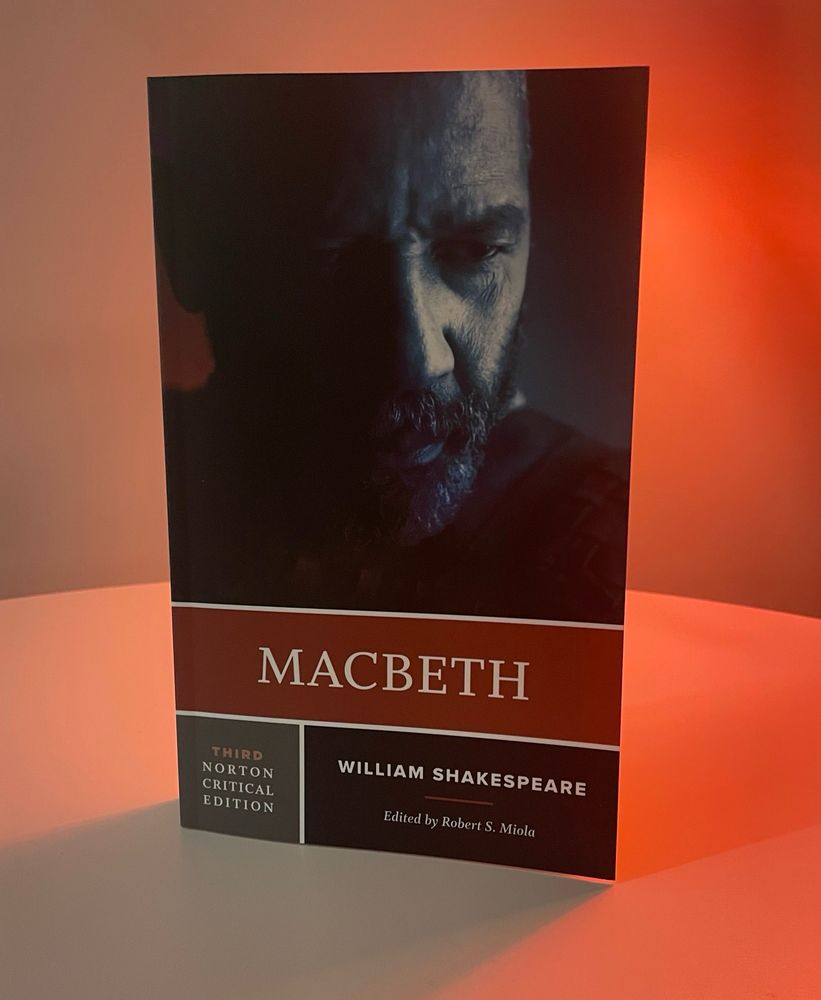 Denzel Washington as Macbeth on the cover of the Norton Critical Edition of Macbeth. The book is on a white table with red backlighting.