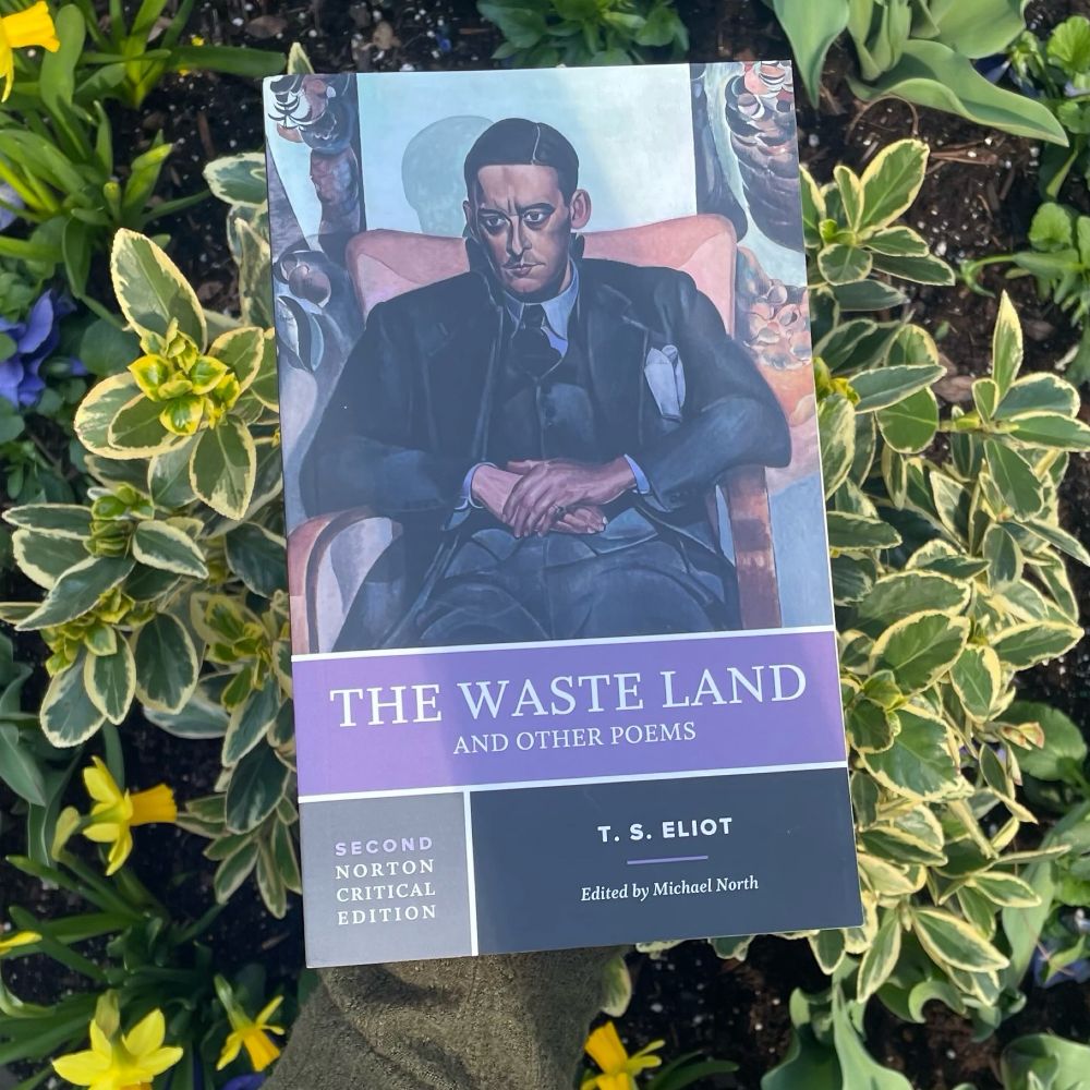 The Waste Land and Other Poems: A Norton Critical Edition held against greenery and flowers. The cover is a portrait of T. S. Eliot sitting in a chair. 
