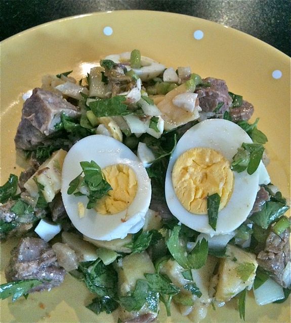 Bord met salade van gekookt rundvlees met daarop een ei.