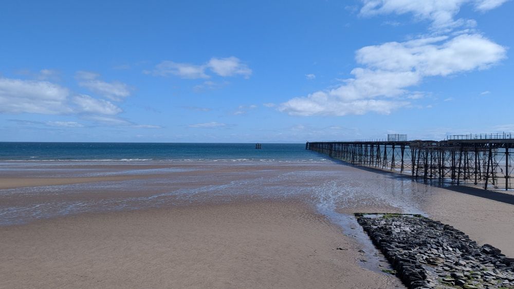 A view over a beach with mountains in the distance across the water
