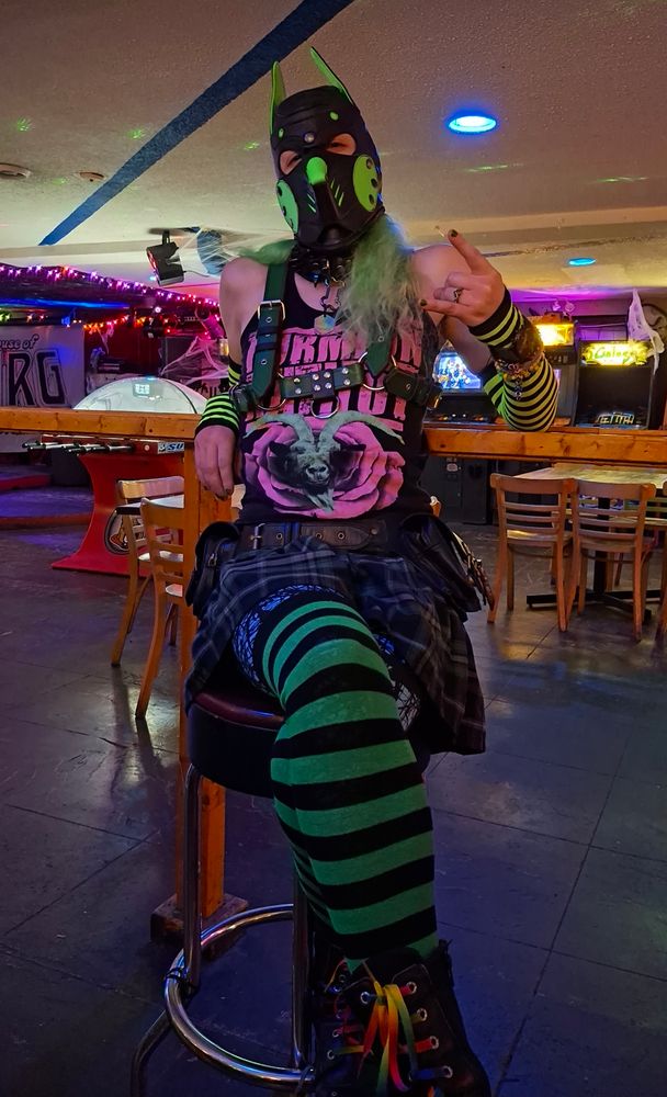 Paradox throwing horns sitting on a stool in an arcade bar