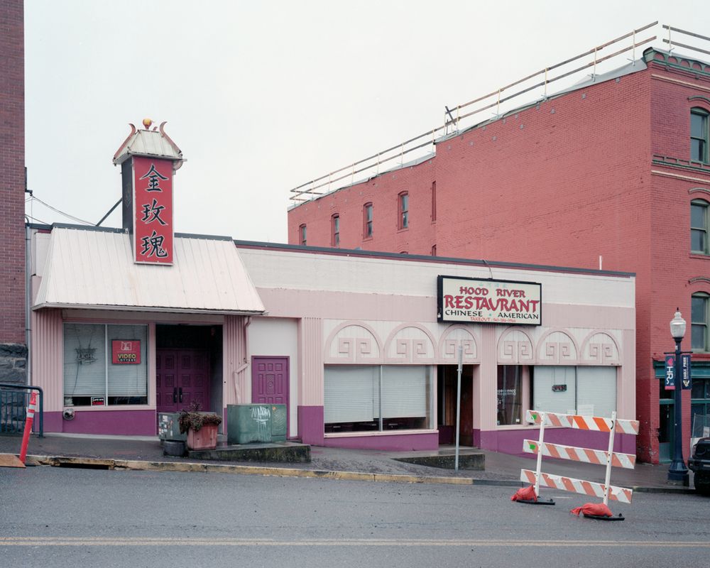 A Chinese restaurant with a construction barricade on the street outside. Brick buildings flank the restaurant on either side.