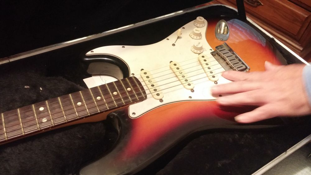 The "sunburst" orange-red-black ombre surface of a classic Fender Stratocaster.