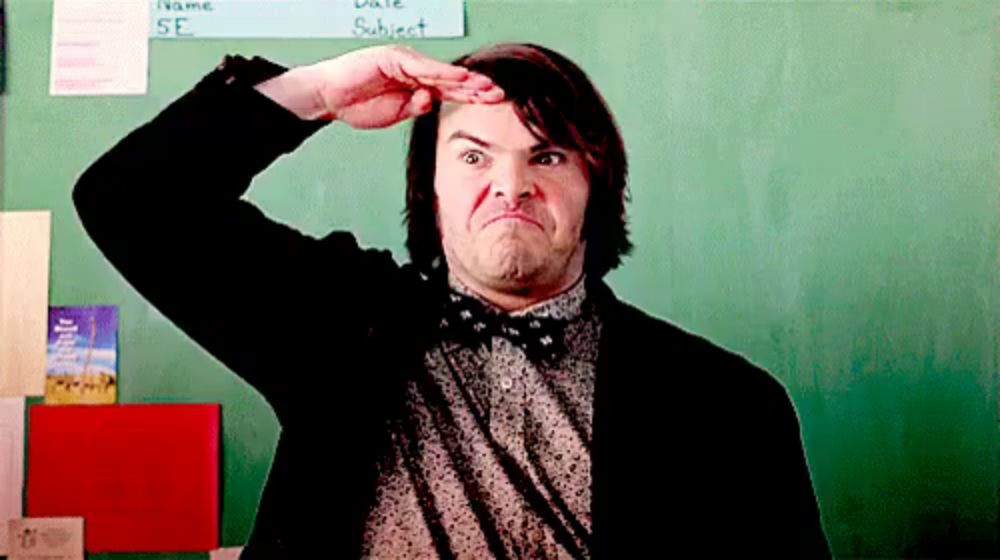 a man in a suit and bow tie is making a funny face in front of a chalkboard .