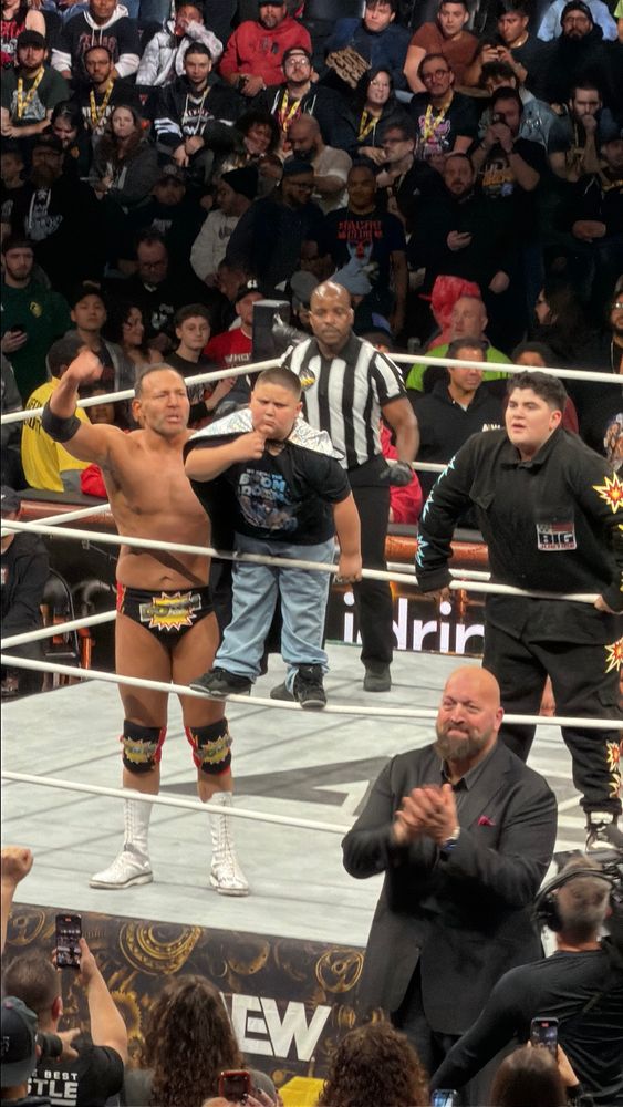 QT Marshall celebrates alongside The Rizzler who stands on the middle rope, while Big Justice stands on the bottom rope and Paul Wight claps. 