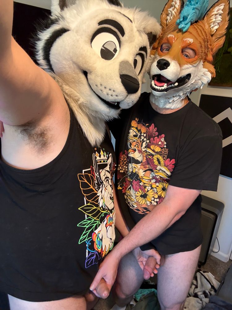 Somnius in fursuit head and a tank top with a very good fox friend in a snapjaw hood that has a blue mohawk—and now both their pants are off and they're pawing each others' cocks~
