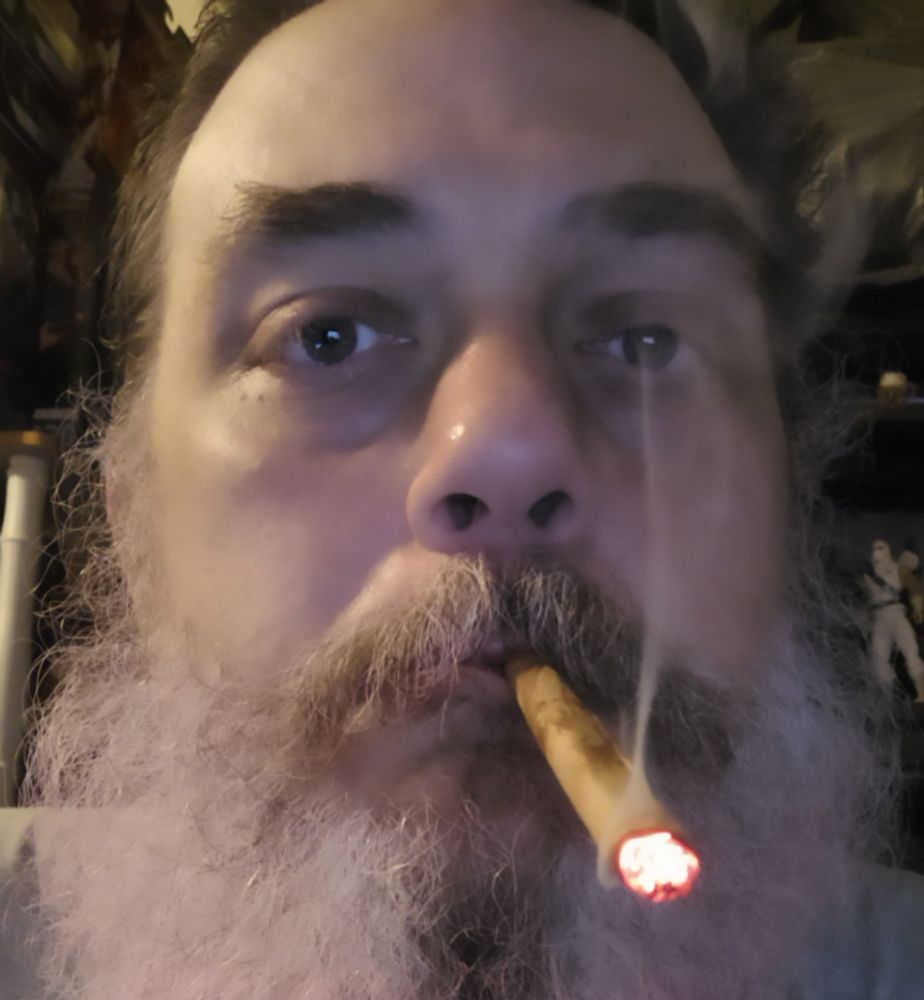 fat white guy with large unkempt white beard smokes a blunt.