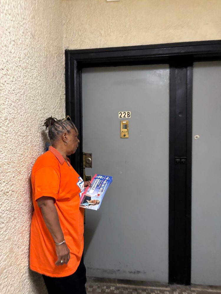 An NYCC member get readys to ring a doorbell inside an apartment building 