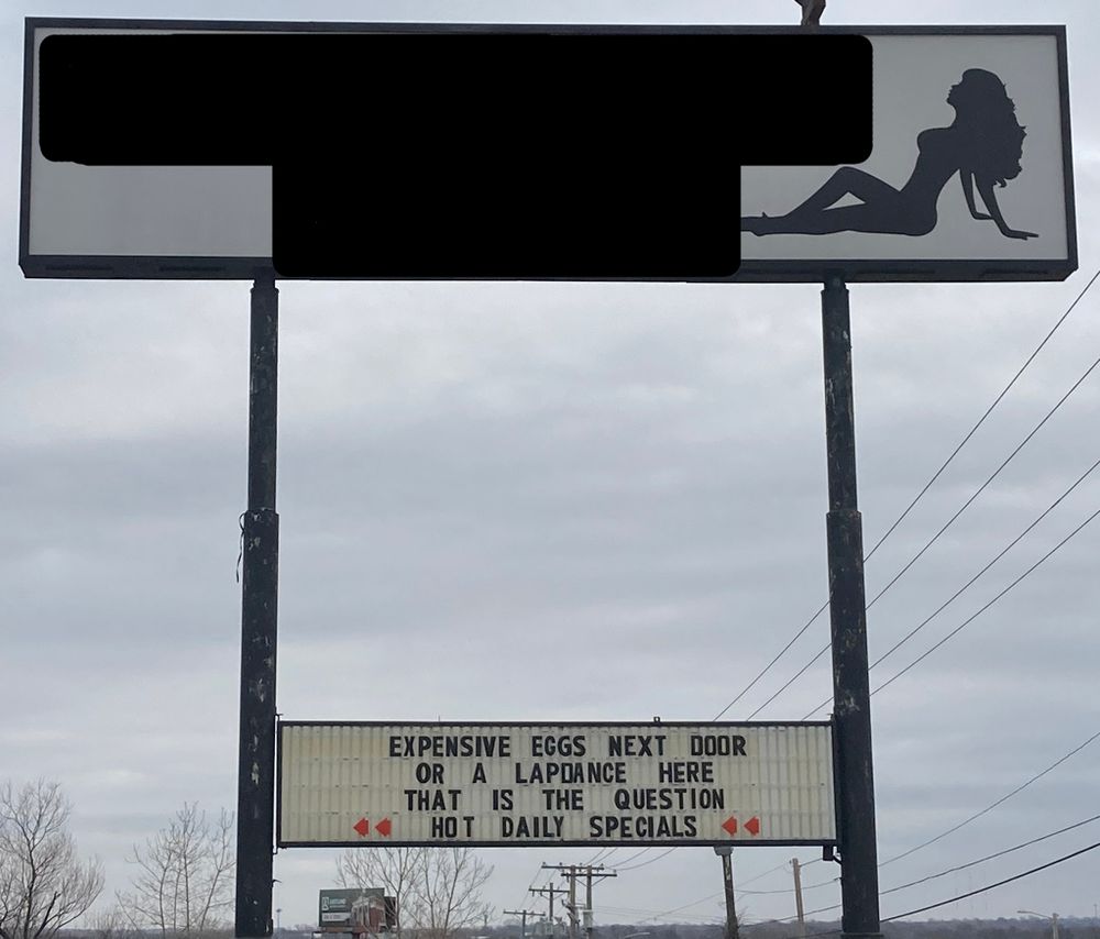 A sign for an strip club with the marquee that reads 'Expensive eggs next door or a lapdance here. That is the question'