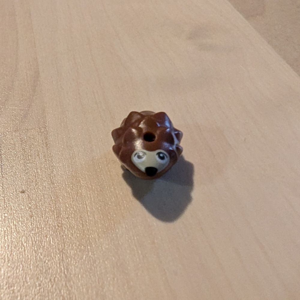 A small brown Lego hedgehog piece with printed eyes and nose facing the camera