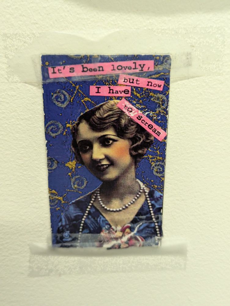 Image shows a picture taped to the wall of a woman from approximately the 1920s with the writing 'It's been lovely, but now I have to scream' on it
