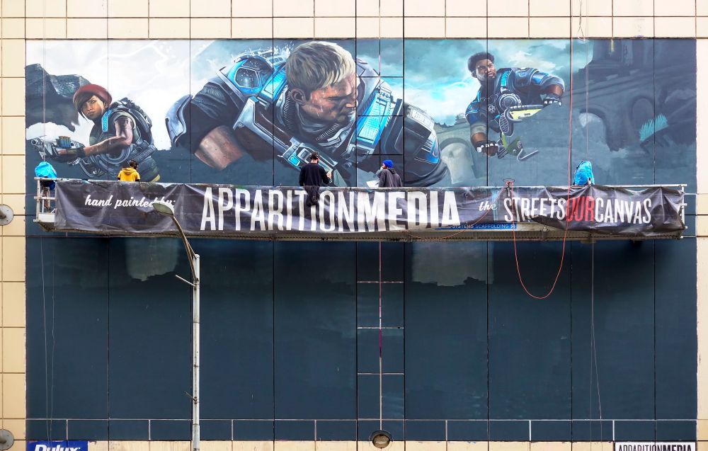 Painters on scaffold painting a poster on a building