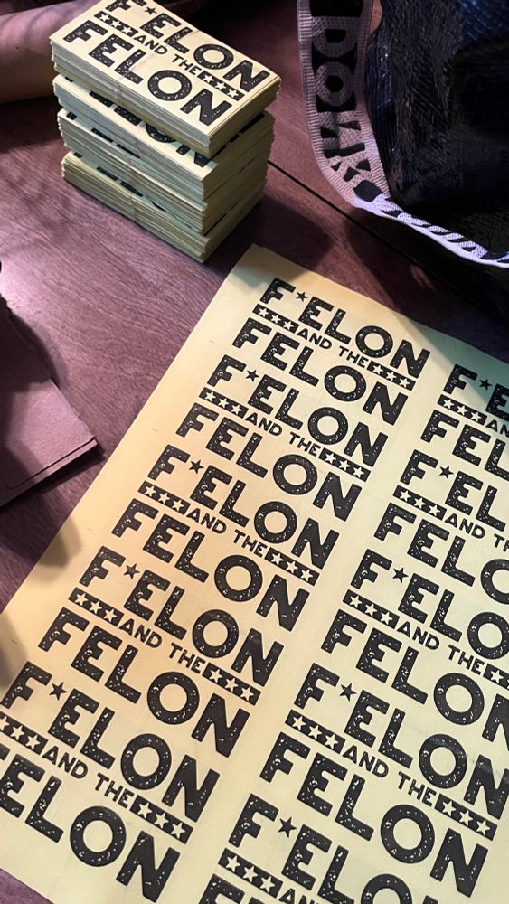 A stack of yellow business cards next to a yellow flier that reads “F Elon and the Felon”