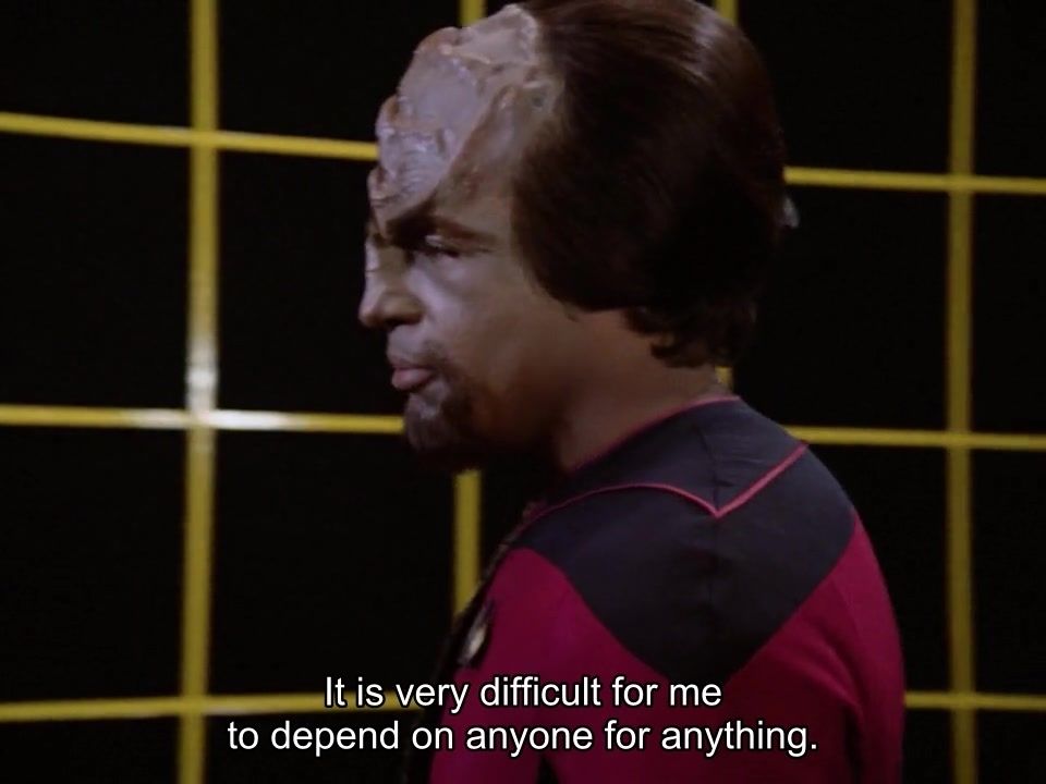 Star Trek The Next Generation scene. We're on the HOLODECK! Which of course we all know is a large square and black cavernous room with yellow gridlines and has many potential uses for scenario roleplay, training, and vacationesque fun and usually is booked out by Riker. Here, Worf is standing, in red uniform. Closed caption reads, "It is very difficult for me to depend on anyone for anything."