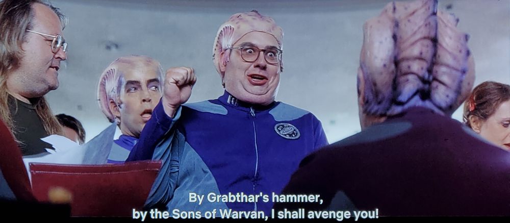 Scene from Galaxy Quest, noted StarTrek film. Pic 1 is an autograph signing, POV is behind a table looking up at convention fans in line. We see a person wearing a light & dark blue sci-fi officer uniform. He's wearing a head piece costume to give an alien appearance that looks like a bald cap with some brain spikes and ridge loaf designed on it. The fellow in line behind him has the same costume. Main super-fan guy is holding his arm and fist up as if giving a pledge or oath, and he looks absolutely possessed with excitement. Like whatever the sci-fi convention version of an "O" face would look like. Closed caption reads, "By Grabthar's hammer, by the Sons of Warvan, I shall avenge you!"
Pic two is reverse angle at the inferred celebrity who is signing autographs. (It's Alan Rickman. RIP, king) He's in the same uniform and bald cap with brain spikes/ridge loaf, but his makeup is much better and more profesh. He is giving an absolute death stare back at nerdy fan guy, and looks like he wants to strangle him. No caption. 