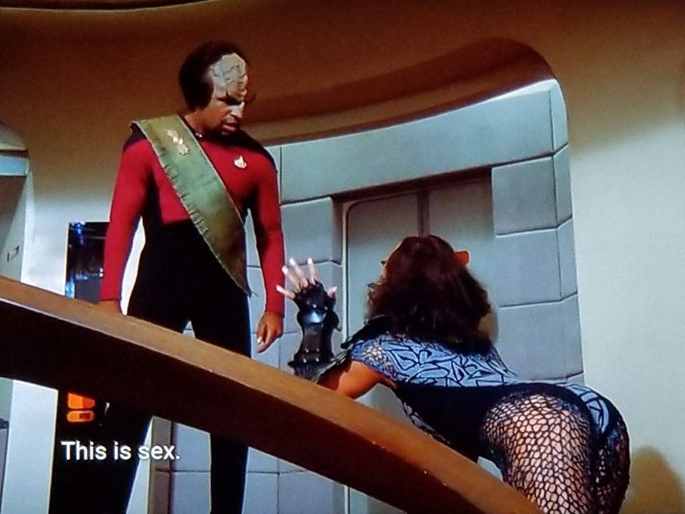 TNG scene. Worf is on the bridge, standing behind that nice wooden smooth curved railing thingy. An unknown female is kind of sort of bent over it here kitty kitty risquè like pointing towards him and dressed like an 80's Def Leopard fan. Worf says, "This is sex. But I have no place for it in my life now!"